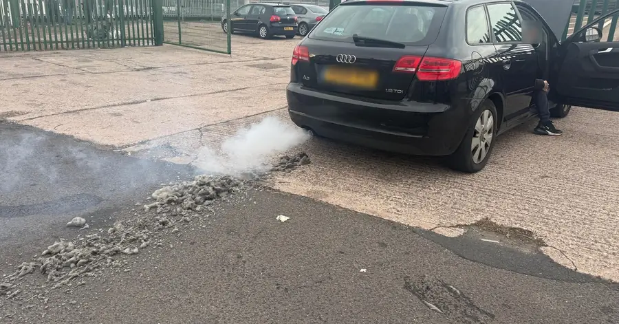 Black Audi A3 with a pile of grey soot on the ground behind the exhaust after a DPF clean